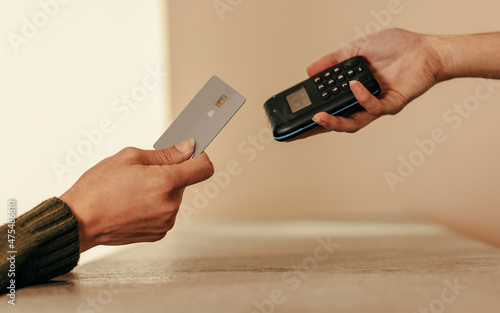 Woman's hand tapping a credit card on a contactless card reader photo