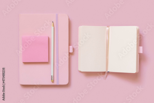 Fotografie Pink notebooks, pencil and paper on light pink top view