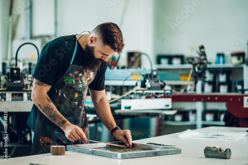 Male worker preparing screen printing film in a workshop