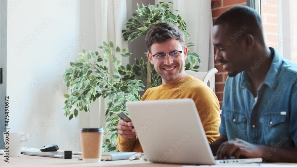 Video of two graphic designer taking a break while looking funny things in mobile phone together in modern startup office. Video of two graphic designer taking a break while looking funny things in mobile phone together in modern startup office.