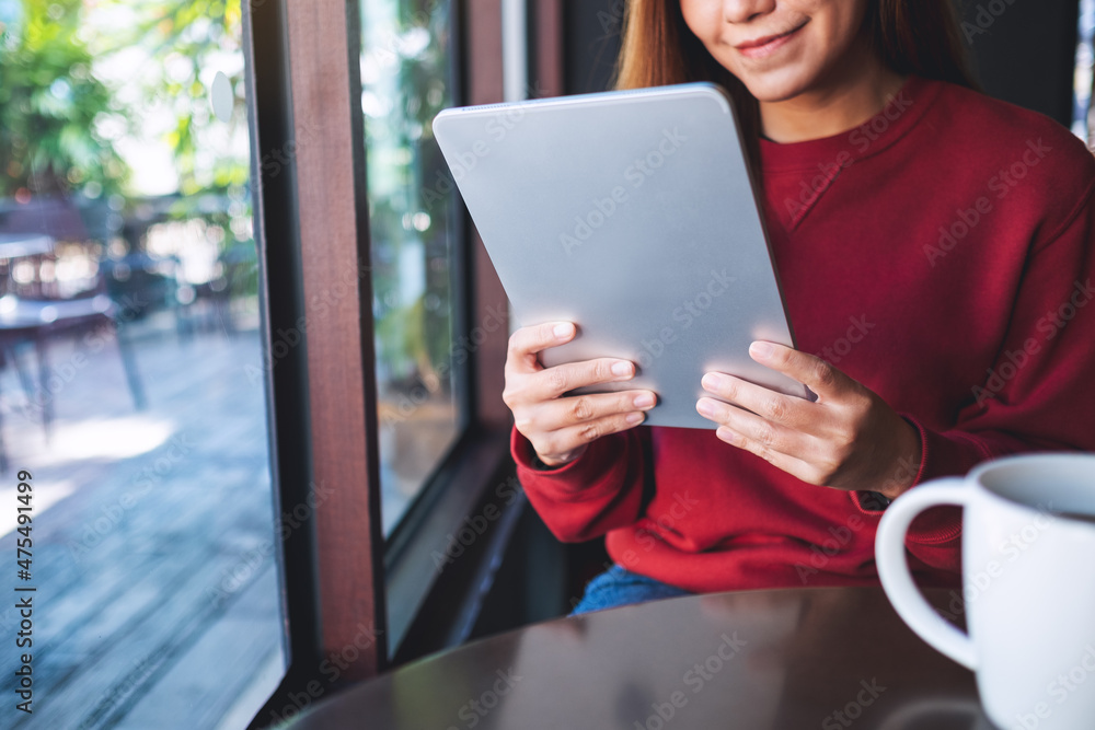 Closeup image of a beautiful young asian woman holding and using digital tablet in cafe Closeup image of a beautiful young asian woman holding and using digital tablet in cafe