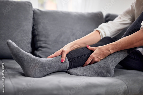 Woman with spasm, cramp, sprained, dislocated ankle, ruptured tendon and joint pain, exercising at home. photo