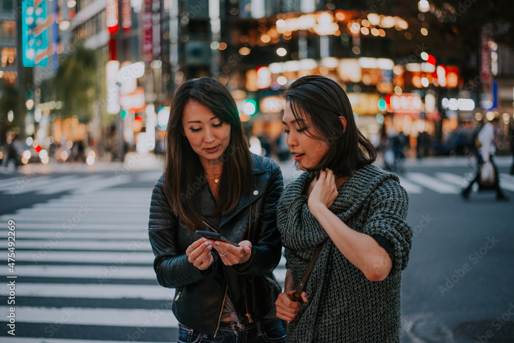 Fototapeta premium Two japanese women around in Tokyo during daytime. Making shopping and having fun