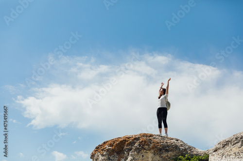 beautiful female traveler standing on top of a mountain on a hike