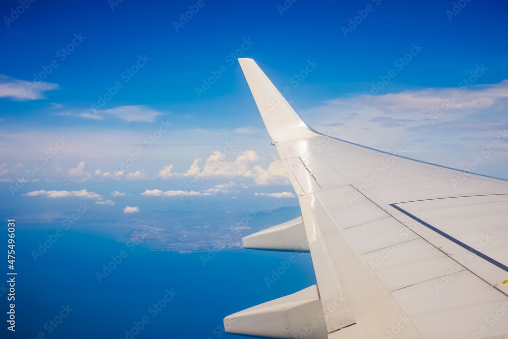 Obraz premium Plane window view with blue sky and clouds.
