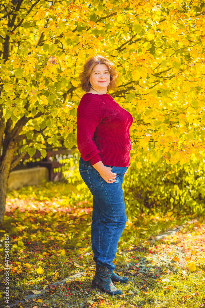 Chubby sunny woman in warm casual clothes in city park. Clothes for plus size ladies Chubby sunny woman in warm casual clothes in city park. Clothes for plus size ladies