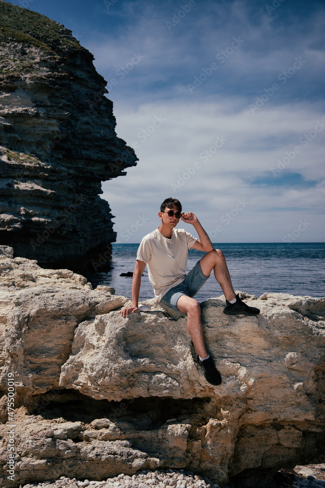 Young man next to the rock and the sea. Travel and vacation.