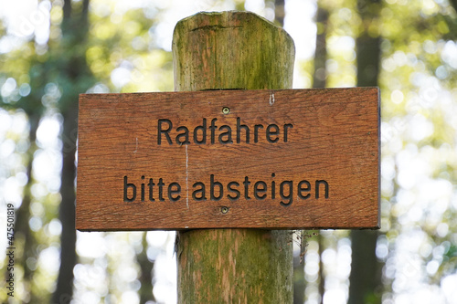 Warning sign made of wood in German. Cyclists please get off.