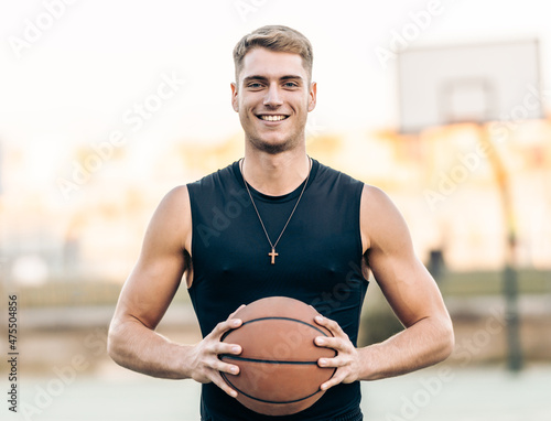 Caucasian athletic man holding a basketball outdoors