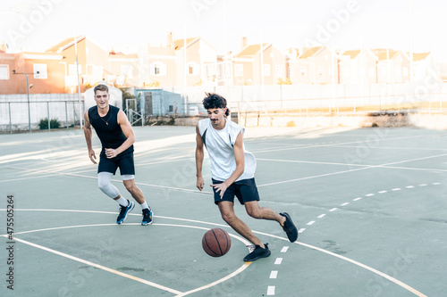 Two man running while playing basketball in an outdoor court © Samuel Perales