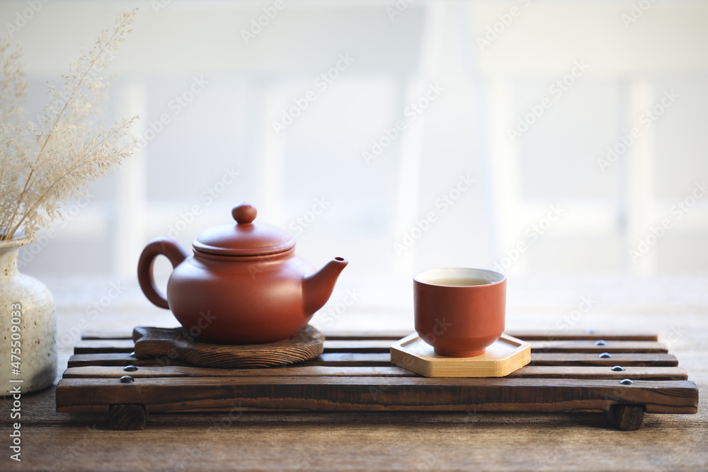 Pottery tea pot and tea cup on wooden tray