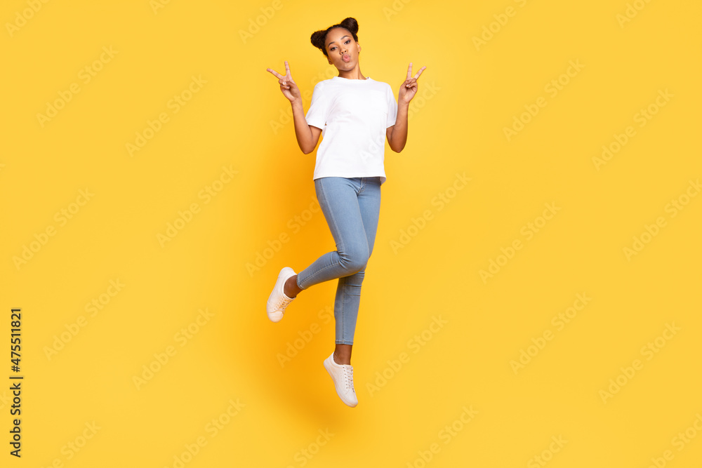 Full length photo of young pretty girl jumper show fingers peace cool v-symbol isolated over yellow color background