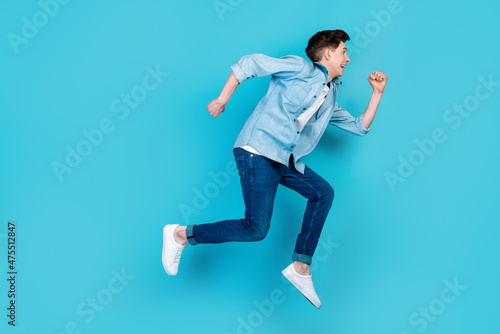 Full body profile side photo of young guy jump run rush look empty space isolated over blue color background
