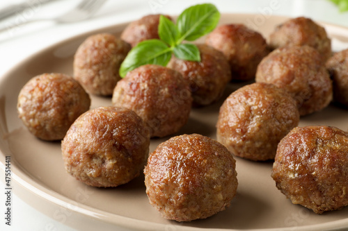 Tasty cooked meatballs with basil on plate, closeup
