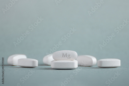 Tablets , vitamins with the abbreviation Mg ( magnesia, macro element magnesium ) on a light background. Copy space.