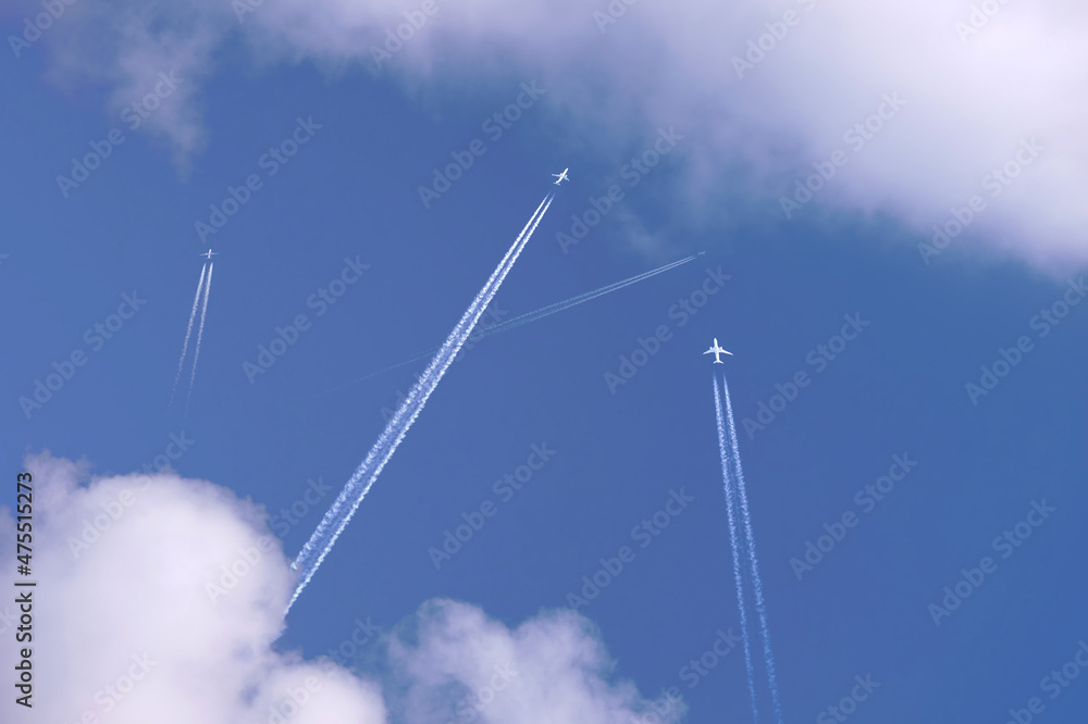 Many distant passenger jet planes flying on high altitude on clear blue sky leaving white smoke trace of contrail behind. Busy air transportation concept Many distant passenger jet planes flying on high altitude on clear blue sky leaving white smoke trace of contrail behind. Busy air transportation concept