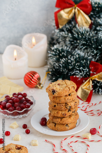 Homemade crunchy cranberry cookies with white chocolate and fresh berry. Delicious healthy dessert. Christmas. New Year. Candles, garlands and Christmas tree toys. Selective focus