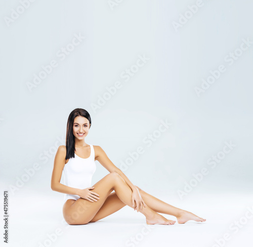 Attractive and slender brunette girl in white underwear posing in studio. Healthy lifestyle, sport and body care concept.