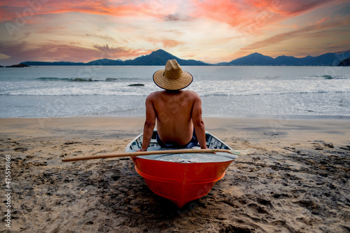 incredible sunset on the beach man on top of a boat on a beach in brazil, ubatuba, sao paulo. photo