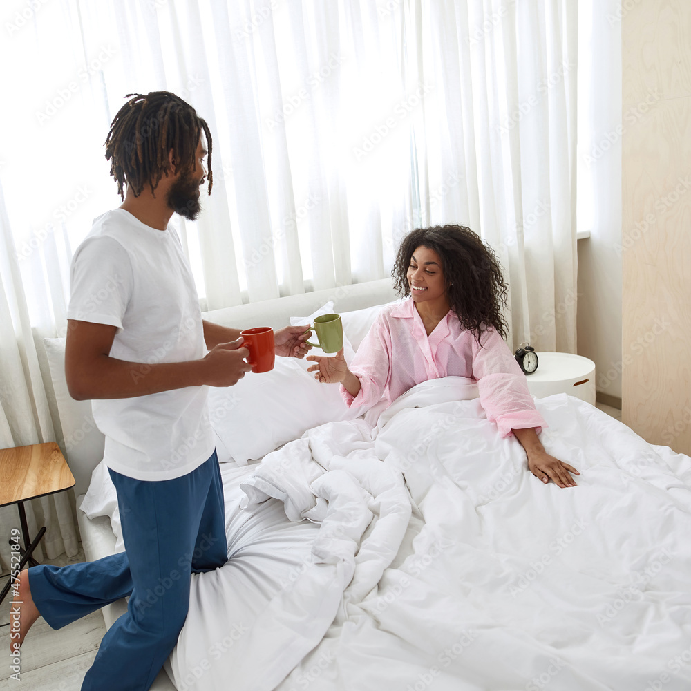 Man giving cup with tea to his girlfriend in bed Man giving cup with tea to his girlfriend in bed