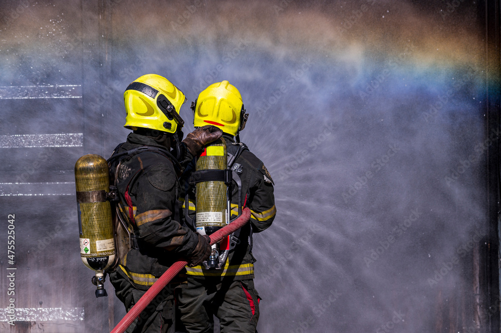 firefighters wearing fire fighter suit for safety and using twirl water ...