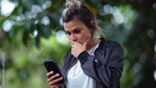 Woman reading shocking message on cellphone message. Surprised emotion to news