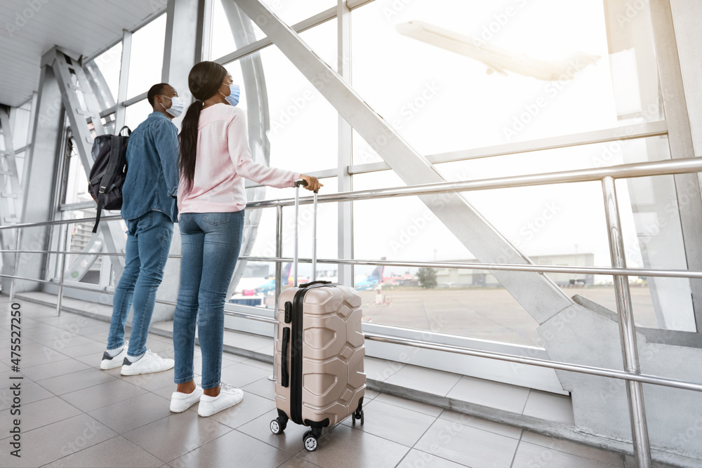 Quarantine Travels. Black Couple In Medical Masks Waiting For Flight In Airport Quarantine Travels. Black Couple In Medical Masks Waiting For Flight In Airport