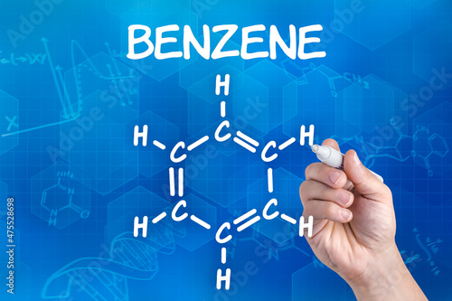 hand with pen drawing the chemical formula of benzene