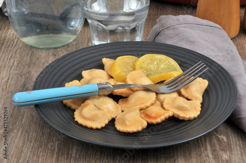 Assiette de raviolis au citron avec une fourchette servie à table avec un verre d'eau photo