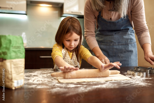 Little girl rolling out dough with rolling pin