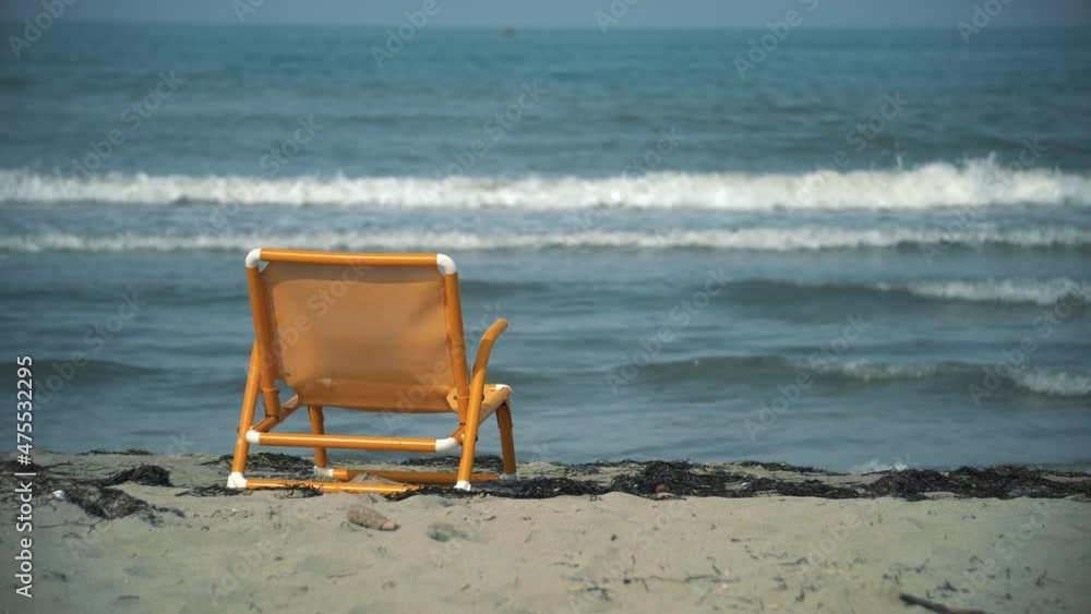 Summer scene on the beach with yellow deck chair and rolling sea waves at background Summer scene on the beach with yellow deck chair and rolling sea waves at background