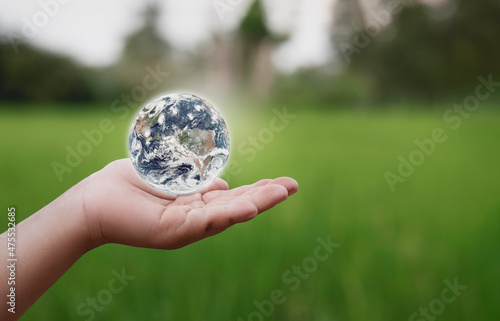 Fototapeta Naklejka Na Ścianę i Meble -  Human hand holding global over green nature background, saving environment, save clean planet, ecology concept. Elements of this image furnished by NASA, 