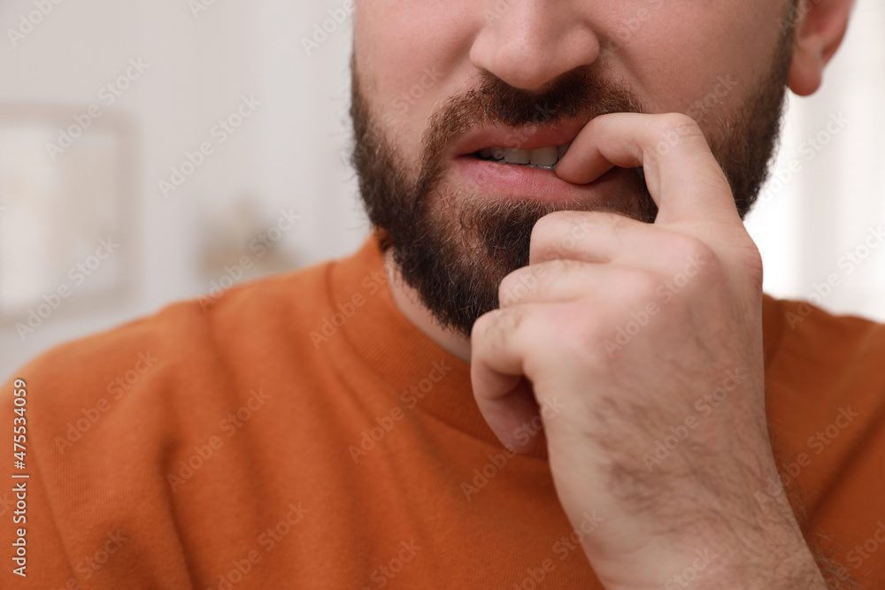 Man biting his nails on blurred background, closeup. Bad habit Man biting his nails on blurred background, closeup. Bad habit