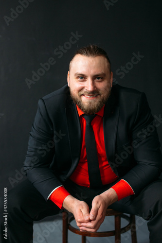 young man, business, sociable speaker, businessman, in a suit with a red shirt, in the studio on a black background.