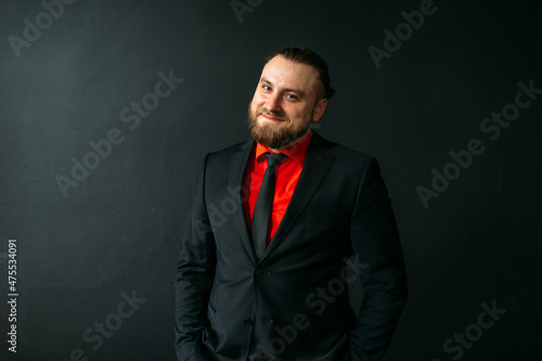 young man, business, sociable speaker, businessman, in a suit with a red shirt, in the studio on a black background.
