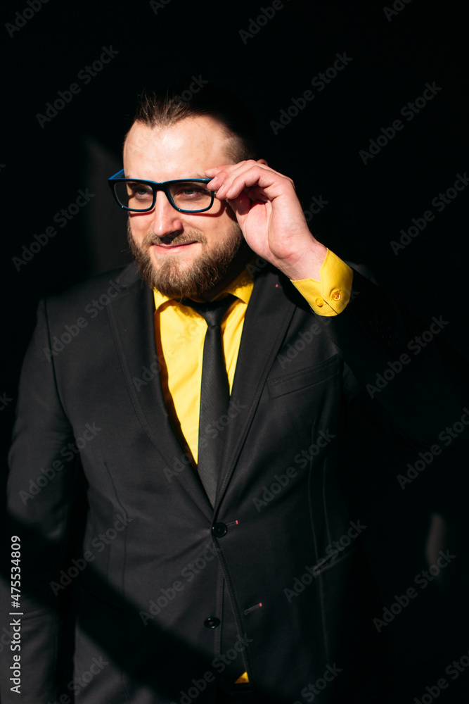 Obraz premium young man, business, sociable speaker, businessman, in a suit with a yellow shirt, in the studio on a black background.