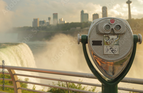 Panoramic View of Niagara Falls at Sunset with binoculars in foreground. Niagara Falls is the largest waterfall in North American, located in Niagara Falls State Park of NY, USA