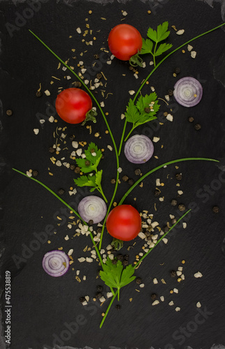 black board with tomatoes, vegetables and spices