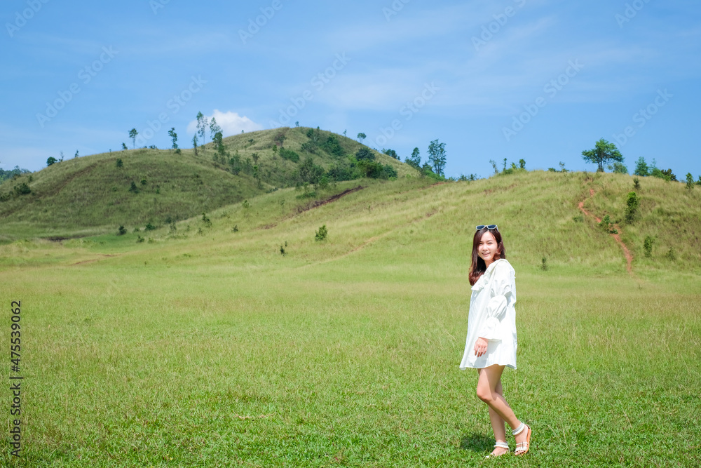 Beautiful Girl stand and acting in front of bald mountain or Phu Khao Ya with green grass field and blue sky. One of natural travel attraction in Ranong province, Thailand Beautiful Girl stand and acting in front of bald mountain or Phu Khao Ya with green grass field and blue sky. One of natural travel attraction in Ranong province, Thailand