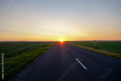 The road leading straight to the rising sun at dawn © gyermol