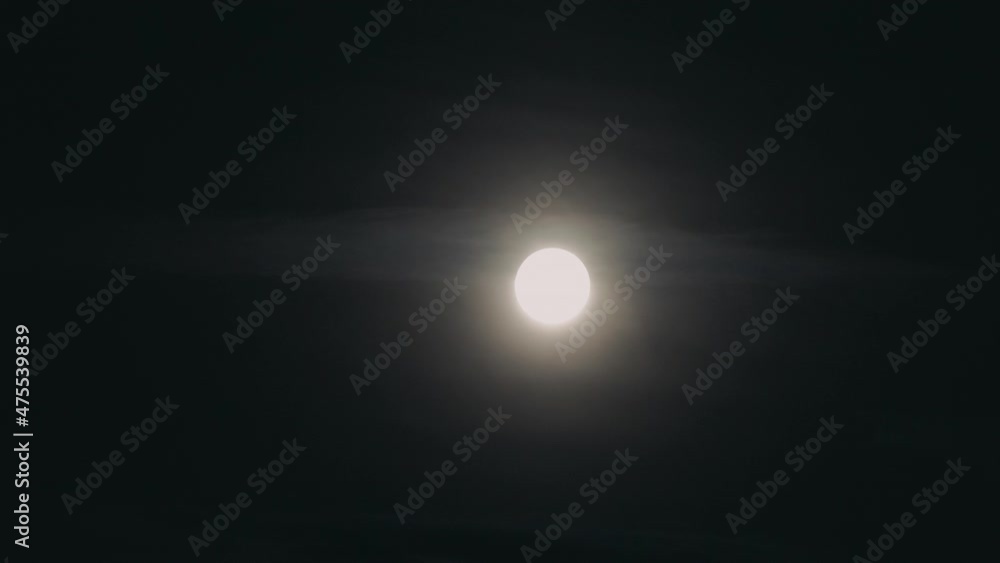 Monochrome time lapse shot of bright moon crossing dark night sky and disappearing in clouds. Monochrome time lapse shot of bright moon crossing dark night sky and disappearing in clouds.