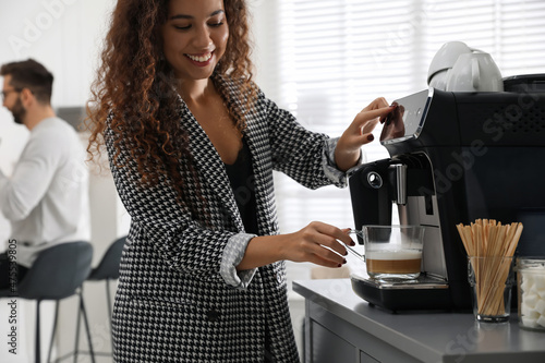 Fotografering African American woman preparing fresh aromatic coffee with modern machine in of