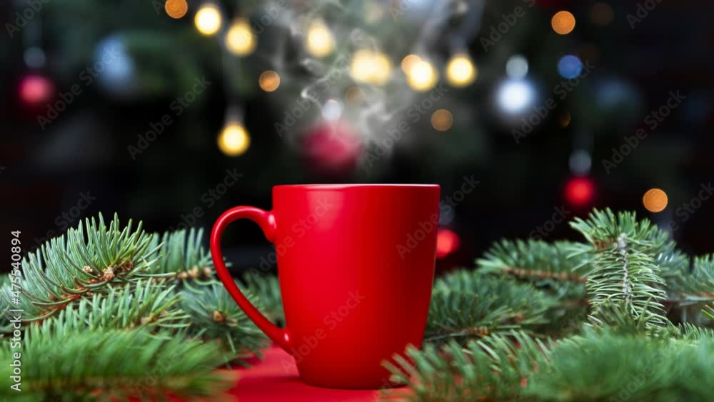 Coffee in a red cup with Christmas tree lights and spruce branches in the background Coffee in a red cup with Christmas tree lights and spruce branches in the background