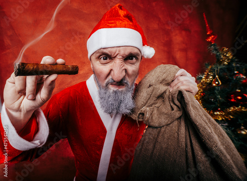 Bad Santa claus smoking a cigar on a red background with christmas decoration