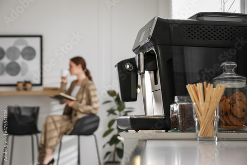 Fotografiet Modern electric coffee machine on table in office. Space for text