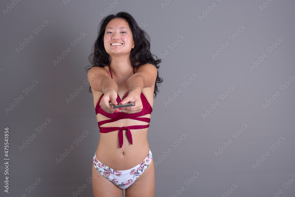 smiling asian girl in bikini, offers electronic device smiling asian girl in bikini, offers electronic device