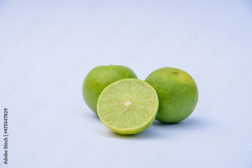 Whole green lime citrus fruit with lime half on white background