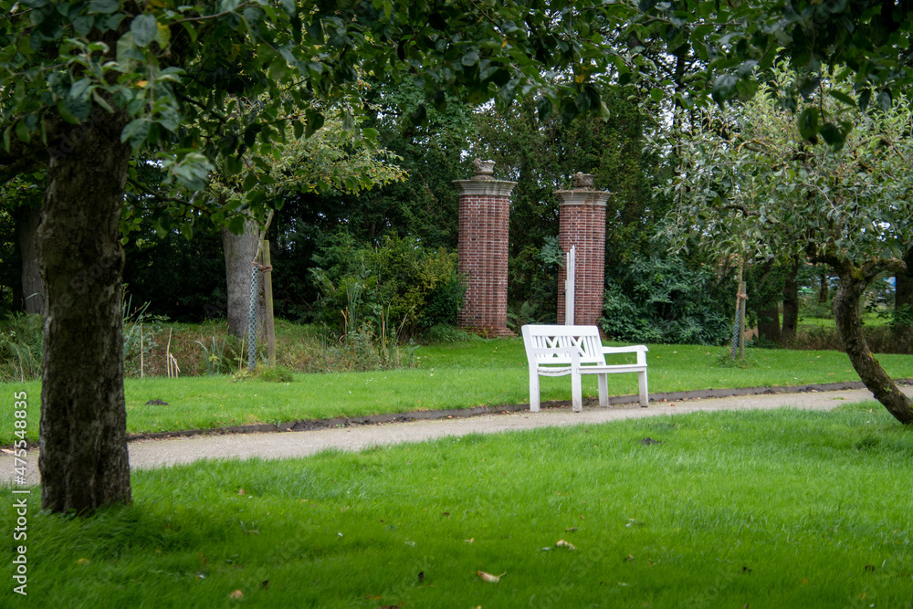 Fototapeta premium Weg im Schlossgarten Lütetsburg mit einer weißen Holzbank
