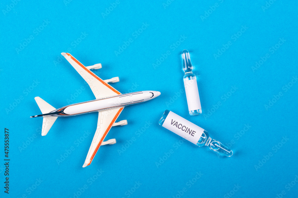 COVID-19 vaccine distribution concept. Airplane model and ampoules with a vaccine on a blue background. COVID-19 vaccine distribution concept. Airplane model and ampoules with a vaccine on a blue background.