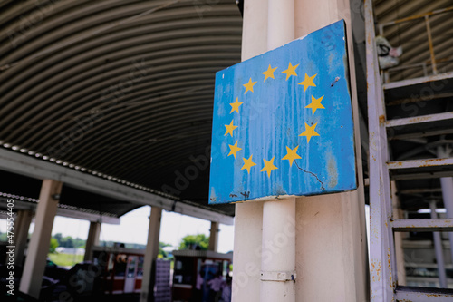 Shallow depth of field (selective focus) image with a worn out and rusty sign at the Romanian border with the European Union symbol.